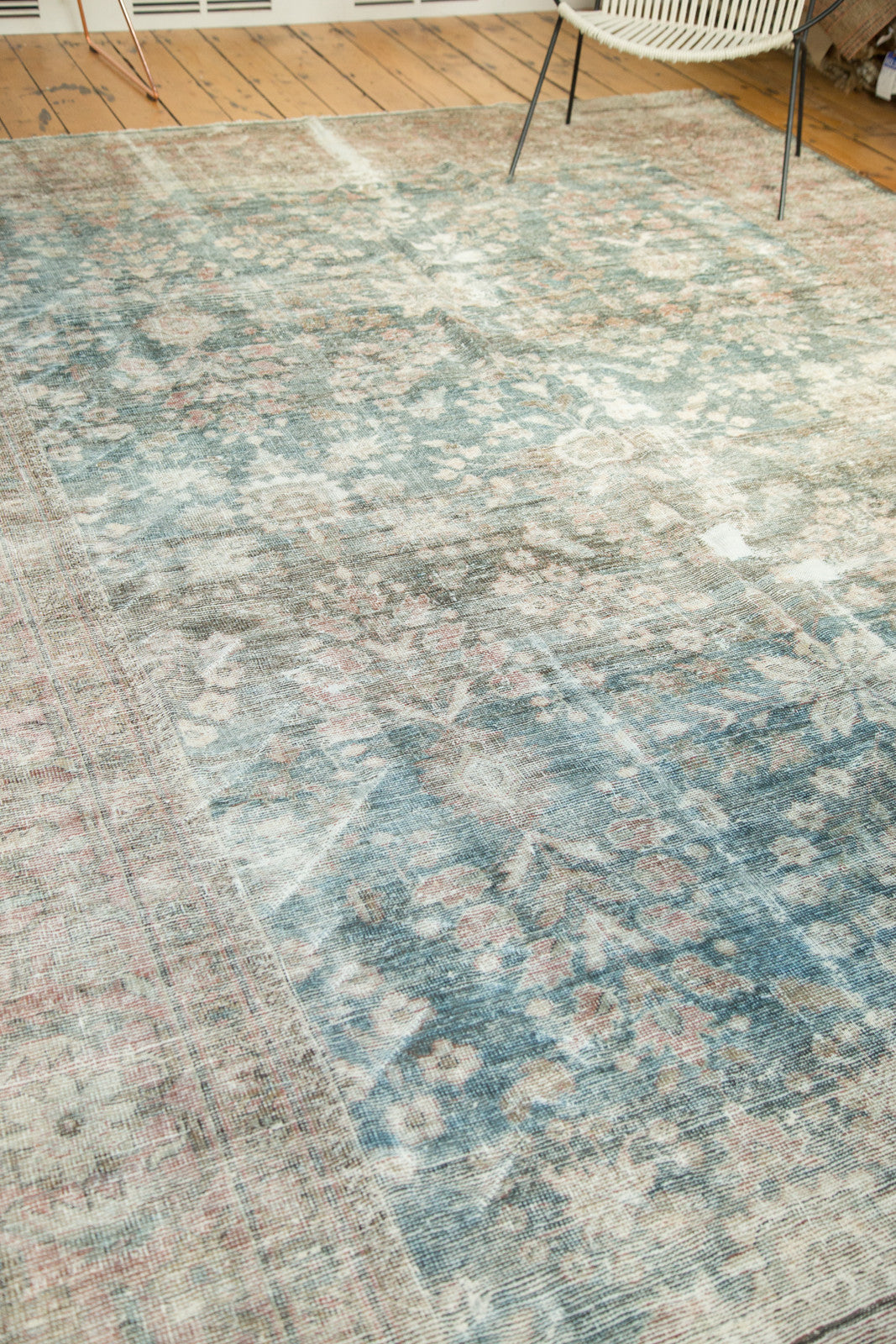 Distressed Mahal carpet's worn pile revealing faded floral blossoms in dusty teal and blush.